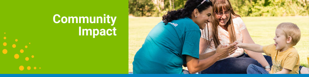 Community Impact webpage header with a Goodwill employee smiling and holding hands with a young boy with his mom in the background.