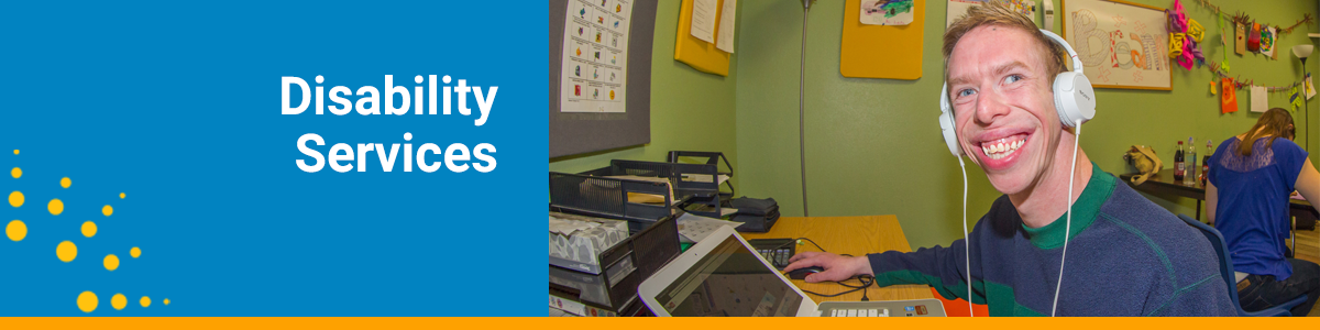 Disability Services webpage header with a man smile while using a laptop and wearing headphones.