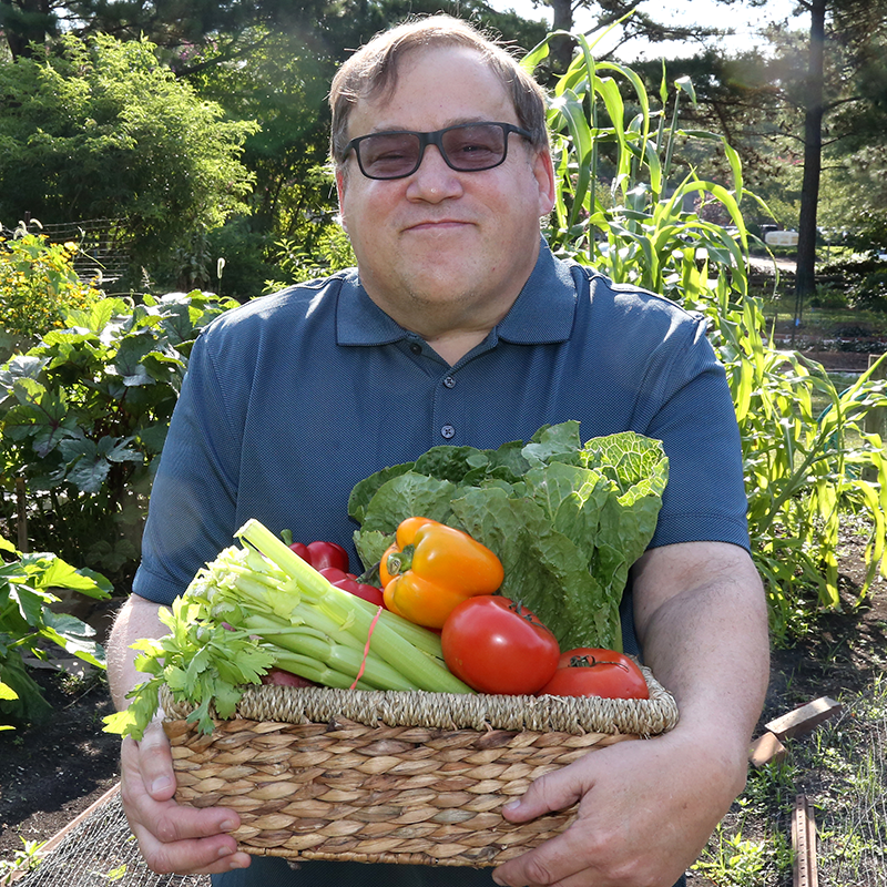 Man with a disability holding a basket of fresh vegetables.