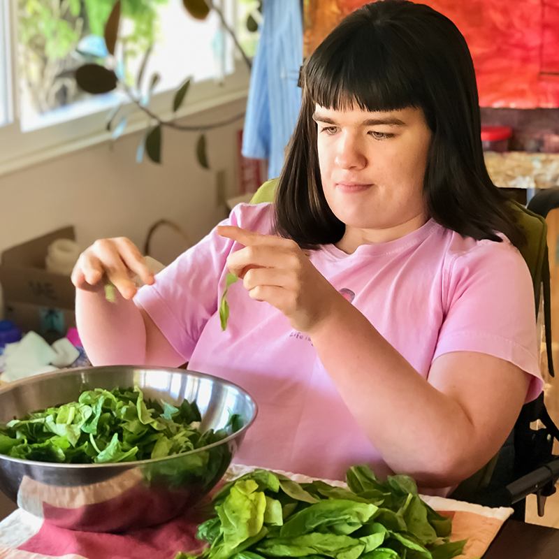 Young woman with a disability making a salad