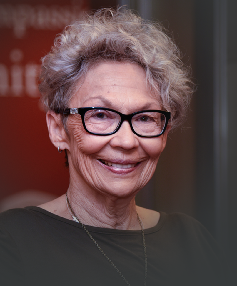 A portrait of lady in a green shirt with glasses.